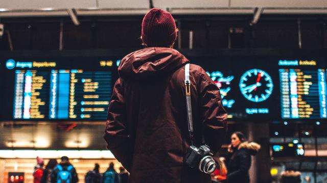 Man standing in front of airport departure board